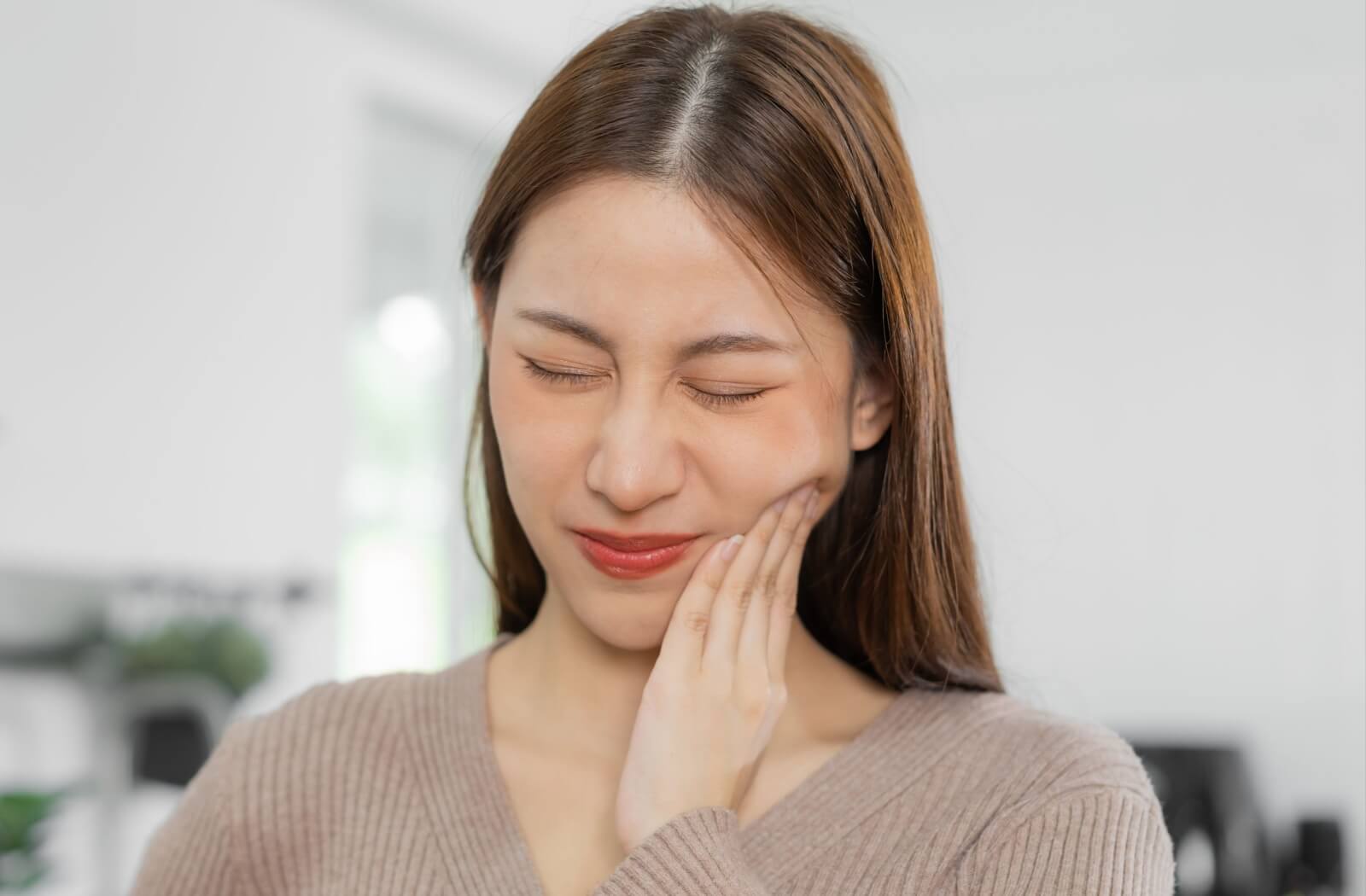 A person rubs their face, uncomfortable from the dental freezing they just received.