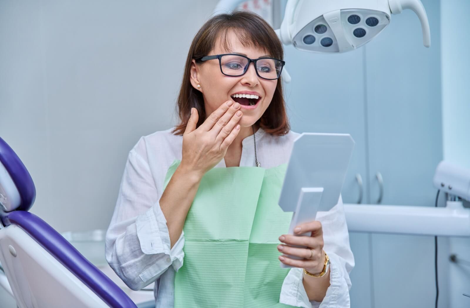 A person sees their dental implants for the first time, seeing the result of their bone graft treatments.